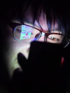 ネット依存のイメージ写真。スマートフォンを暗闇で見る人（宮崎瑞穂撮影）