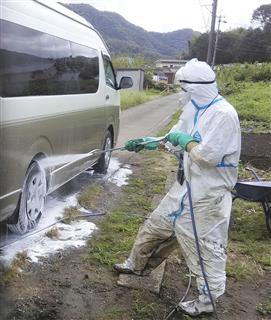 豚コレラのウイルス感染が確認された養豚場周辺で、畜産関係者の車両を消毒する岐阜県職員＝９日、岐阜市（県提供）