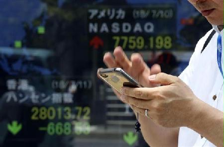 東京都内でスマートフォンを使う男性。東京の通信料金は国際的に高水準だ（ＡＰ）