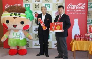 徳川デザインのボトルを福田富一知事（左）に贈呈するコカ・コーラボトラーズジャパンの柴康裕東日本営業本部長＝２日、県庁（楠城泰介撮影）