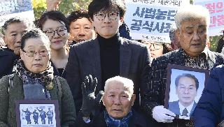 ３０日、判決が言い渡される前に韓国最高裁前で集会を開く原告側の支援者ら。中央下は原告の李春植さん（共同）