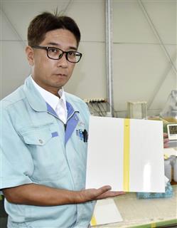 実験中の保護材を塗布した板を手にする、九州ハイテックの宮園将聖さん=鹿児島市 実験中の保護材を塗布した板を手にする、九州ハイテックの宮園将聖さん=鹿児島市