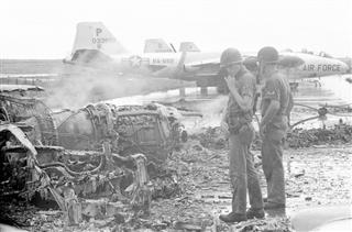 ベトナム南部ビエンホアにあった米軍基地で、攻撃を受けて残骸となった爆撃機を見つめる米兵＝１９６４年（ＡＰ＝共同）