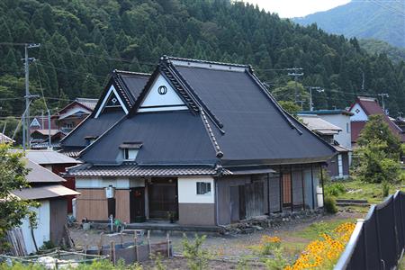 トタンを巻いた茅葺き屋根の家屋。下の部分もきれいな状態で保存されており、集落の規模も大きい