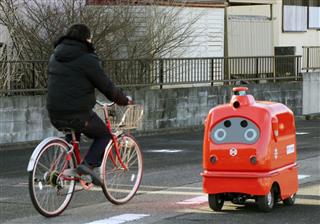 福島県浪江町の自動車学校で、自転車とすれ違う自動走行ロボット＝３１日午前