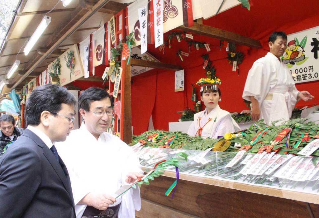 浅草神社の矢野幸士禰宜（左端）に福笹を紹介する西宮神社の吉井良英権宮司＝１月１１日、兵庫県西宮市