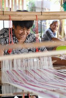 タイ東北部ウドンタニ県コーケオ村で機織りをするナリーさん（左）＝２２日（共同）