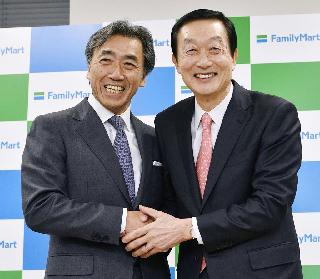 記者会見で握手するファミリーマートの沢田貴司社長（左）とユニー・ファミリーマートＨＤの高柳浩二社長＝１０日午後、東京都港区