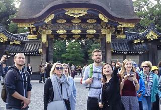 女性ガイドから英語で二条城の案内を受ける外国人観光客＝京都市中京区