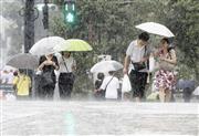 土砂降りの雨の中を歩く人たち＝８日午前、東京都品川区