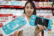 発売された携帯専用の新型ゲーム機「ニンテンドースイッチ　ライト」を手にする購入者＝２０日午前、大阪市のヨドバシカメラマルチメディア梅田