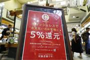 １日、消費税率が１０％に引き上げられ、ポイント還元ができるキャッシュレス決済サービスの対象店舗に掲げられたポスター＝大阪市
