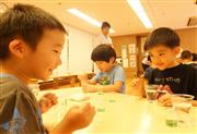 水の入ったコップに短い毛糸を入れて、水に浮く様子を観察＝東京都港区の「にじのいるか保育園　芝浦」