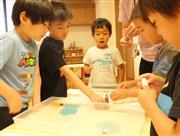 マーブリングの実験。表面張力と界面活性剤による模様の変化に興味津々＝東京都港区の「にじのいるか保育園　芝浦」