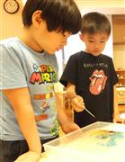 水面に絵の具を浮かせ、洗剤を付けた竹串で表面をつついて模様の変化を観察する園児＝東京都港区の「にじのいるか保育園　芝浦」