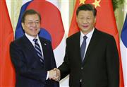 握手する中国の習近平国家主席（右）と韓国の文在寅大統領＝２３日、北京（聯合＝共同）