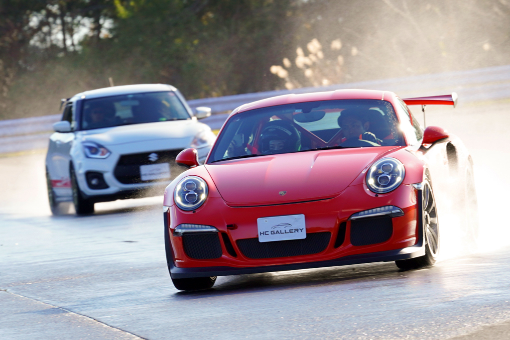 ウェット路を疾走するポルシェ「911 GT3 RS」と、スズキ「スイフトスポーツ」のコンプリートカー