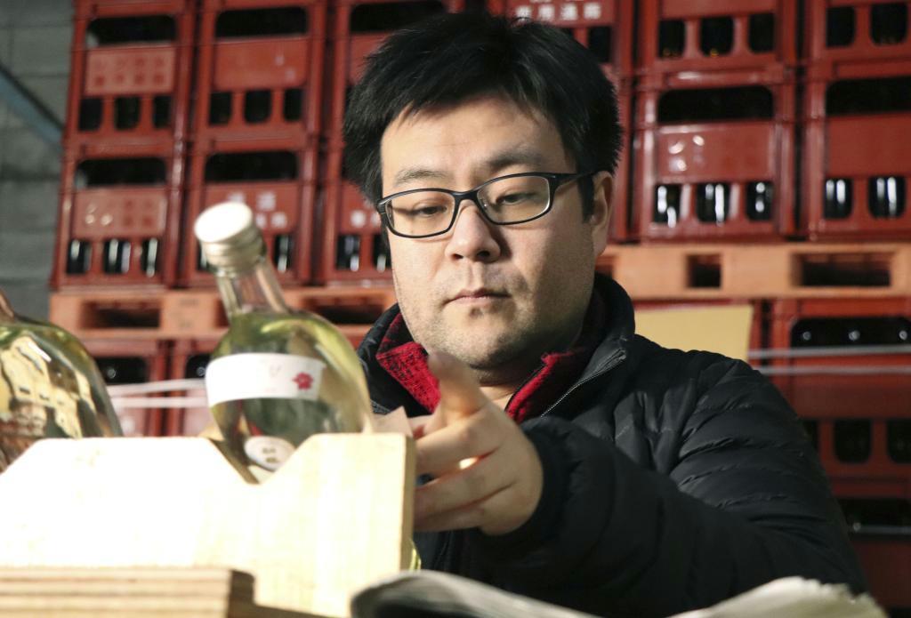 「酔人日」のボトルにラベルを貼る「初桜酒造」４代目の笠勝敦夫さん＝和歌山県かつらぎ町