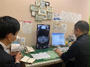 担当の本間義崇医師（右）からＣＴ検査の結果について説明を受ける坂井広志記者＝１月７日、東京・築地の国立がん研究センター中央病院