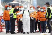 基隆港に停泊しているクルーズ船に乗るために待機する防護服を着た防疫作業員ら＝２日、台湾（ＡＰ）
