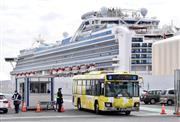 クルーズ船「ダイヤモンド・プリンセス」が停泊する大黒ふ頭から出発するバス。下船者を乗せているとみられる＝１９日午前、横浜市鶴見区（鴨川一也撮影）