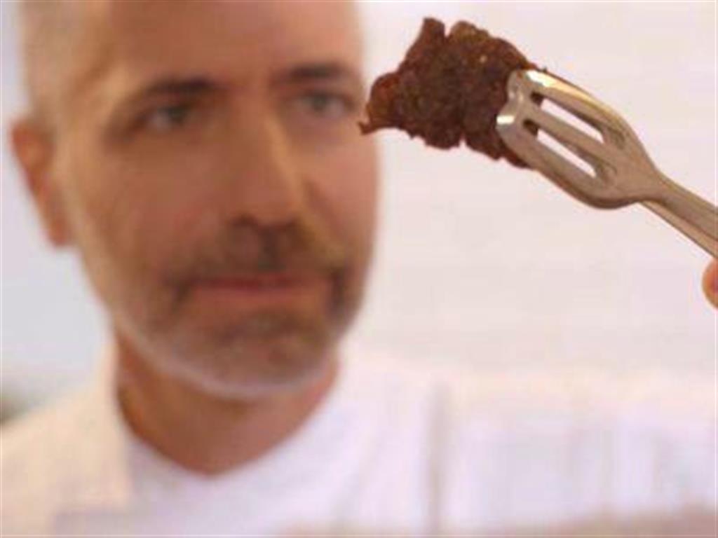 「培養肉のステーキ」を持つ料理人(同社提供・共同)