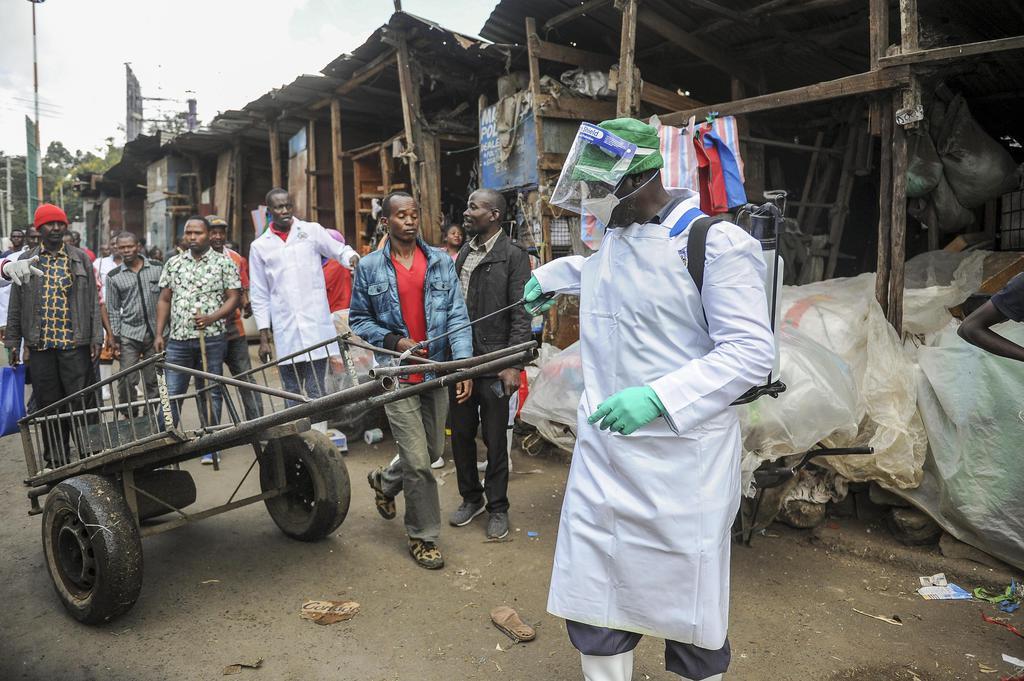 ２１日、ケニアの首都ナイロビの屋外市場で、手押し車に消毒剤をかける保健省当局者（ＡＰ＝共同）