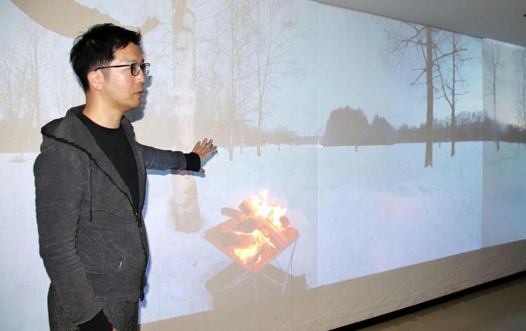 森林の映像が投影された部屋で「デジタル森林浴」について説明する辻木勇二代表＝北海道帯広市（ｆｏｒｅｓｔｄｉｇｉｔａｌ提供）