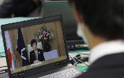 小池百合子都知事からのメッセージが動画中継され、配属先の総務局で新入職員を代表して視聴する男性職員（手前）＝１日午前、東京都新宿区（納冨康撮影）