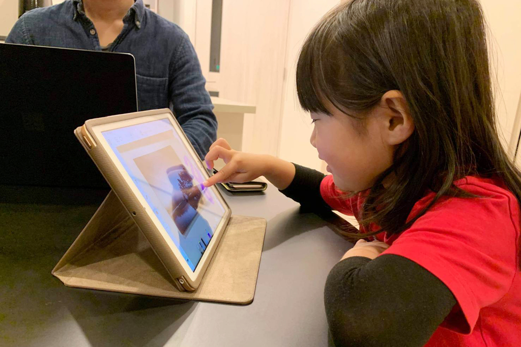 ひとつのテーブルで、オンライン授業を受けるA子ちゃん（手前）と家で仕事をするA子ちゃんのお父さん。提供：GGIS