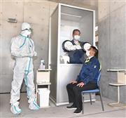 集合検査場では、ボックスの中から手を伸ばして検体を採取する実演が行われた＝２３日午後、横須賀市救急医療センター（今野顕撮影）