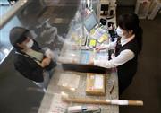 ビニールのカーテン越しに接客する郵便局員（右）＝３日午後、東京都千代田区の東京中央郵便局（佐藤徳昭撮影）