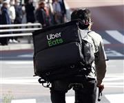 自転車で東京都内を走る「ウーバーイーツ」の配達員＝４月、東京都新宿区