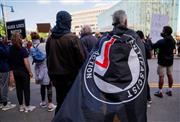 抗議デモのそばで「アンティーファ（ＡＮＴＩＦＡ）」の旗を身にまとう男性（手前）＝５月３１日、ボストン（ロイター）