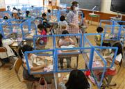 卓上シールドが設置された机で給食を食べる新１年生たち＝三重県亀山市立亀山西小学校