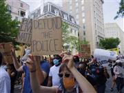 首都ワシントンで「警察予算を打ち切れ」のプラカードを掲げて行進するデモ参加者（黒瀬悦成撮影）