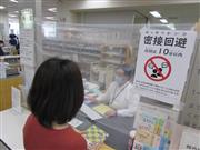 ビニールシートで飛沫を遮断しながら返却などの対応をする大阪市立中央図書館のカウンター職員＝大阪市西区