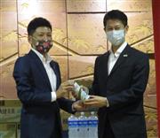 湯崎知事（右）に再稼働した初回製造品を渡す升井工場長＝広島県庁