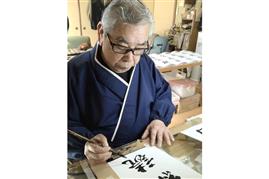 書体のもとになる筆文字を書く綱紀栄泉さん。84歳の今も毎日50字を書き、新しい書体を作り続けている