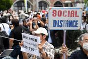 東京都知事選候補者の街頭演説を聞く有権者に、距離を開けるよう促す選挙事務所の関係者＝１８日午後、東京・港区のJR新橋駅前（酒巻俊介撮影）