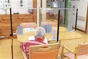 デイサービス利用者が使う机の上には、飛沫防止用のアクリル板が置かれている＝１日、東京都世田谷区