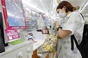 購入した商品をマイバッグに入れる買い物客＝１日、東京都品川区のローソンＴＯＣ大崎店