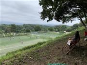 アローレ八王子スポーツクラブの敷地内のベンチで休む子供。下のフィールドではトップチームと会員たちが汗を流す＝８月１９日、東京都八王子市（筆者撮影）