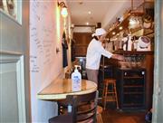 大阪市中央区の飲食店では、入り口に消毒液を置き、扉も開けて営業していた＝１２日午後（宇山友明撮影）
