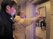 繁華街ススキノ地区を巡回する北海道と札幌市の職員。バーの入り口の張り紙で営業時短要請に応じていることを確認した＝１３日午後１０時３５分（寺田理恵撮影）