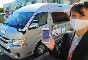 ＮＴＴドコモが海浜幕張地域で実証実験中のＡＩ運行バスは、スマートフォンで乗車を予約する＝２１日、千葉市美浜区
