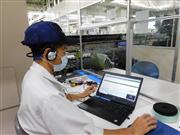 工場の稼働状況を遠隔監視している社員から指示を受ける現場社員＝９日、神奈川県厚木市のリコー厚木事業所（黄金崎元撮影）