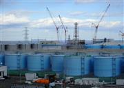 処理水を貯めるタンクが立ち並ぶ東京電力の福島第一原子力発電所。奥が水素爆発した１号機（代表撮影）