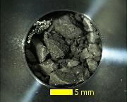 はやぶさ２が２回目の着地で採取した小惑星リュウグウの試料。人工の金属片のような物質（左上）も入っていた（ＪＡＸＡ提供）