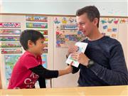 先生と一緒に本を読む生徒。先生は挿絵を手で隠して、文字を読んでいるかを試しているのです。提供：GGIS